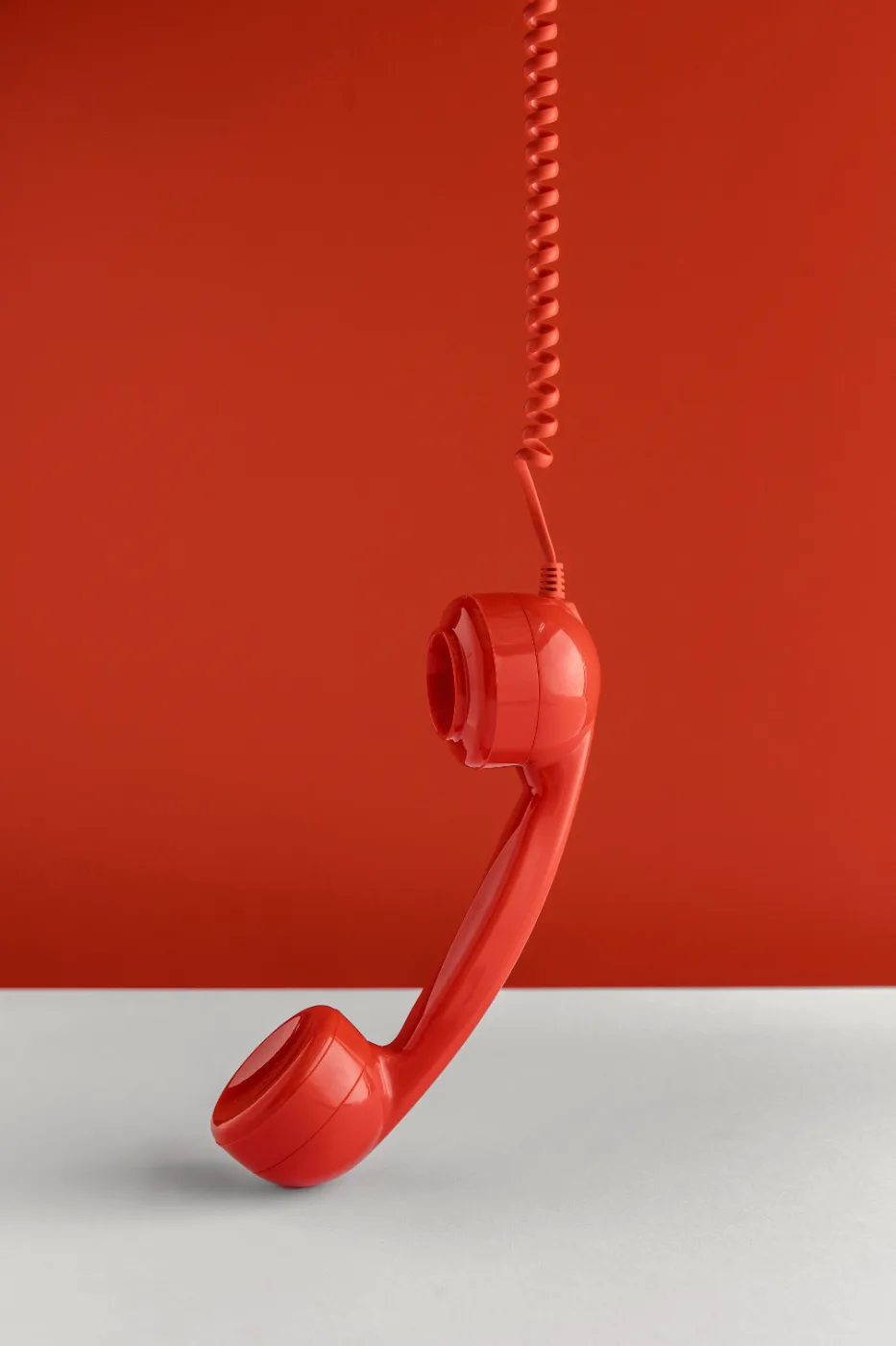 Roter Telefonhörer vor rotem Hintergrund